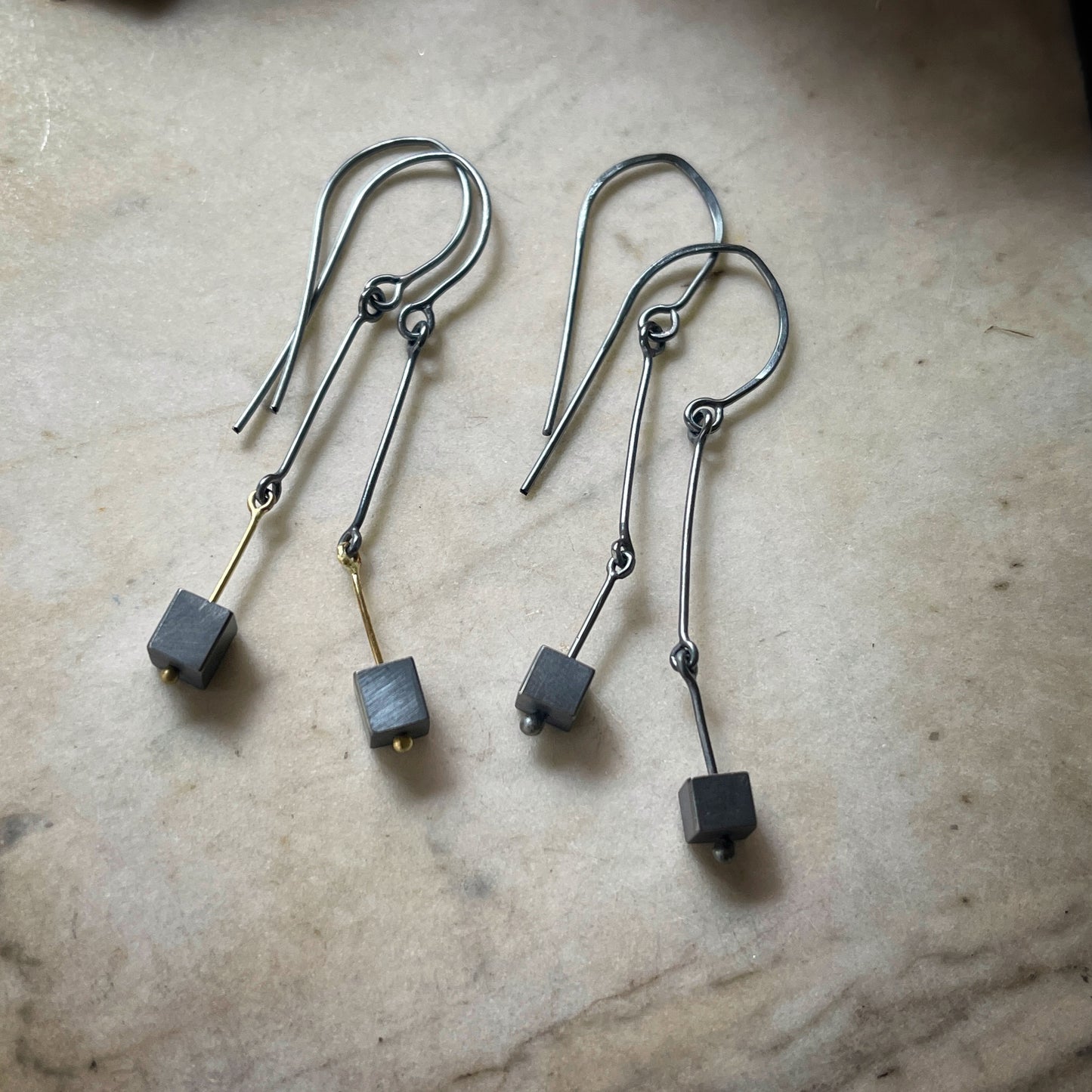 earrings in oxidized silver and gold wirh darkened silver cubes dangling at the end