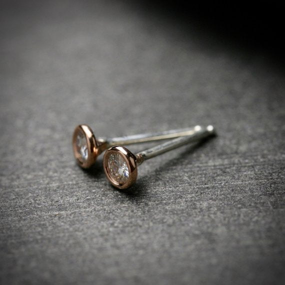 14k rose gold 3mm Moissanite stud earrings. They are bezel set.