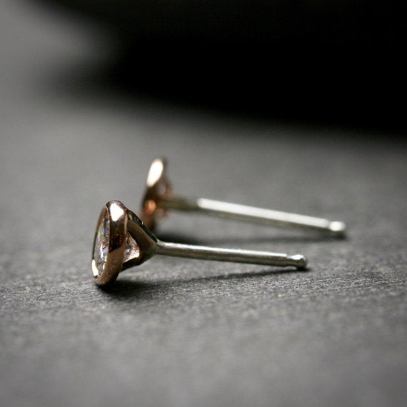 side view of 14k rose gold 3mm Moissanite stud earrings. They are bezel set.