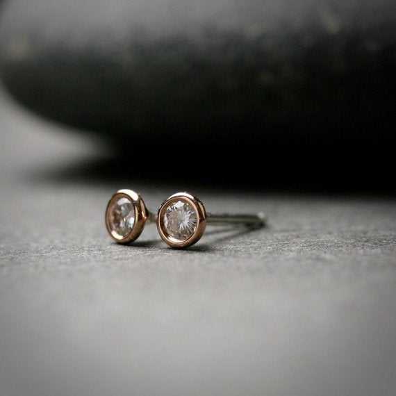 14k rose gold 3mm Moissanite stud earrings. They are bezel set.