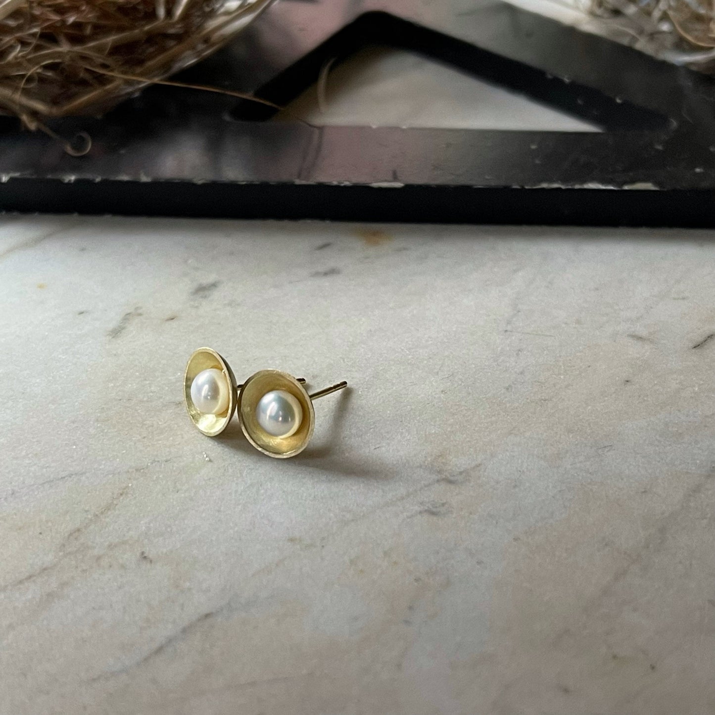 white pearls sit in yellow gold cups