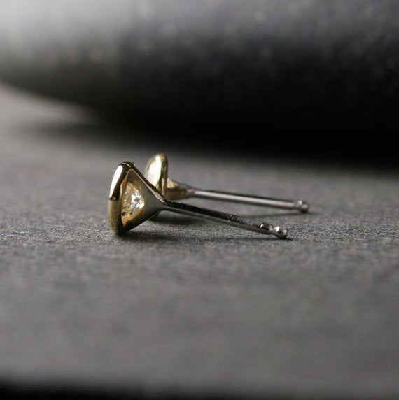 a pair of yellow gold Moissanite stud earrings shown from the side to show sterling silver posts