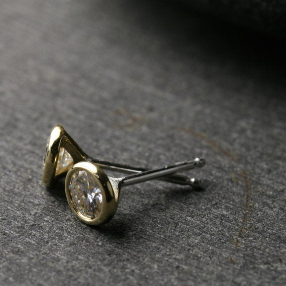 a pair of yellow gold Moissanite stud earrings shown from the side to show sterling silver posts