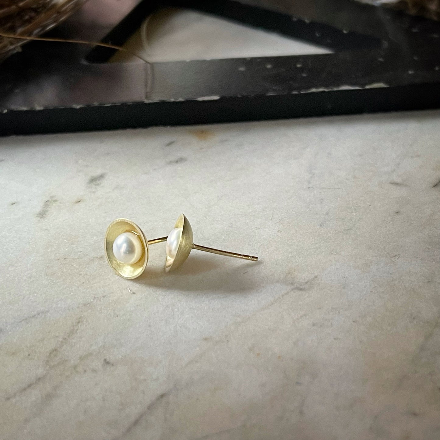 yellow gold and pearl earrings shown from the side
