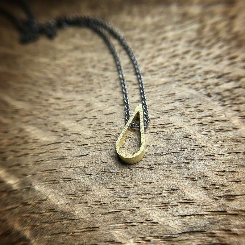tiny 18k yellow gold teardrop shaped pendant with a hammered texture. Sterling silver oxidized chain.