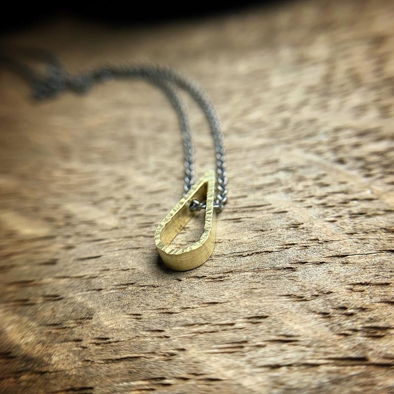 Small teardrop shaped 18k yellow gold pendant with oxidized silver chain.