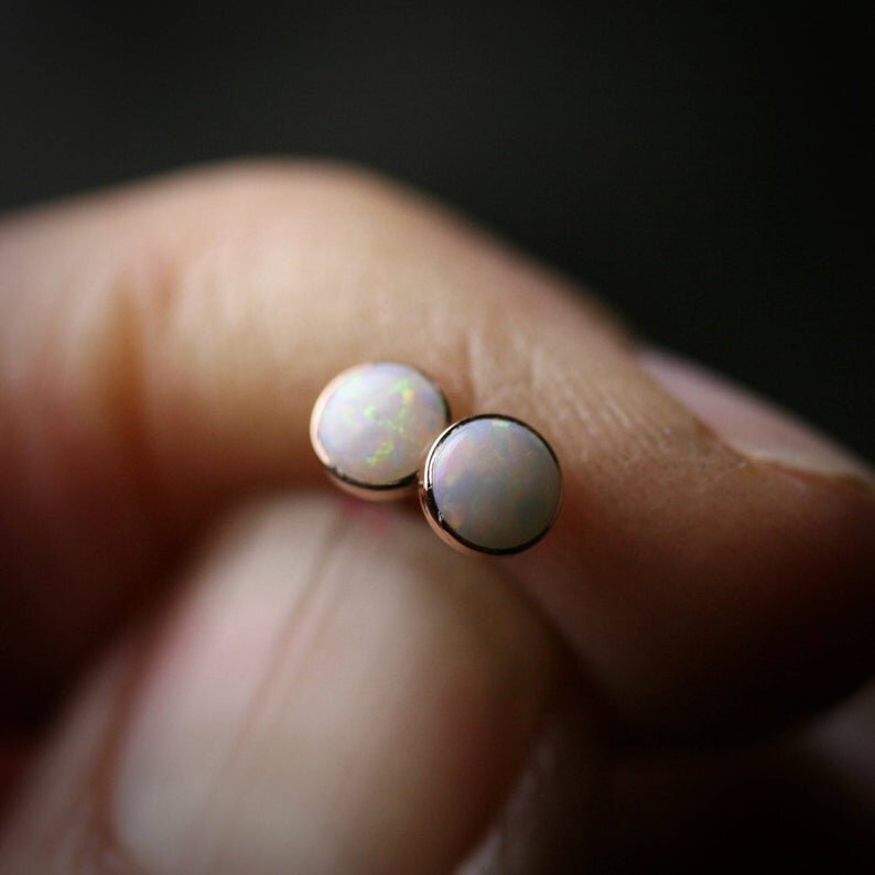 4mm opal earrings with rose gold bezels. Shown held in a hand for scale