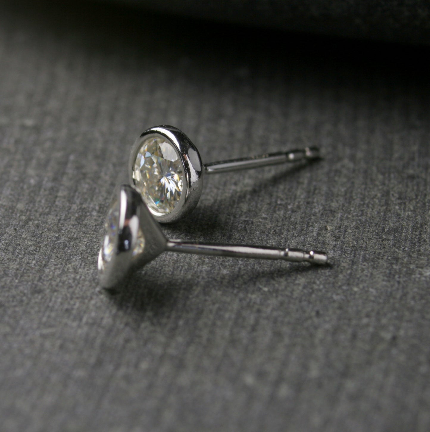 5mm bezel set Moissanite stud earrings in sterling silver. Shown from the side to show posts