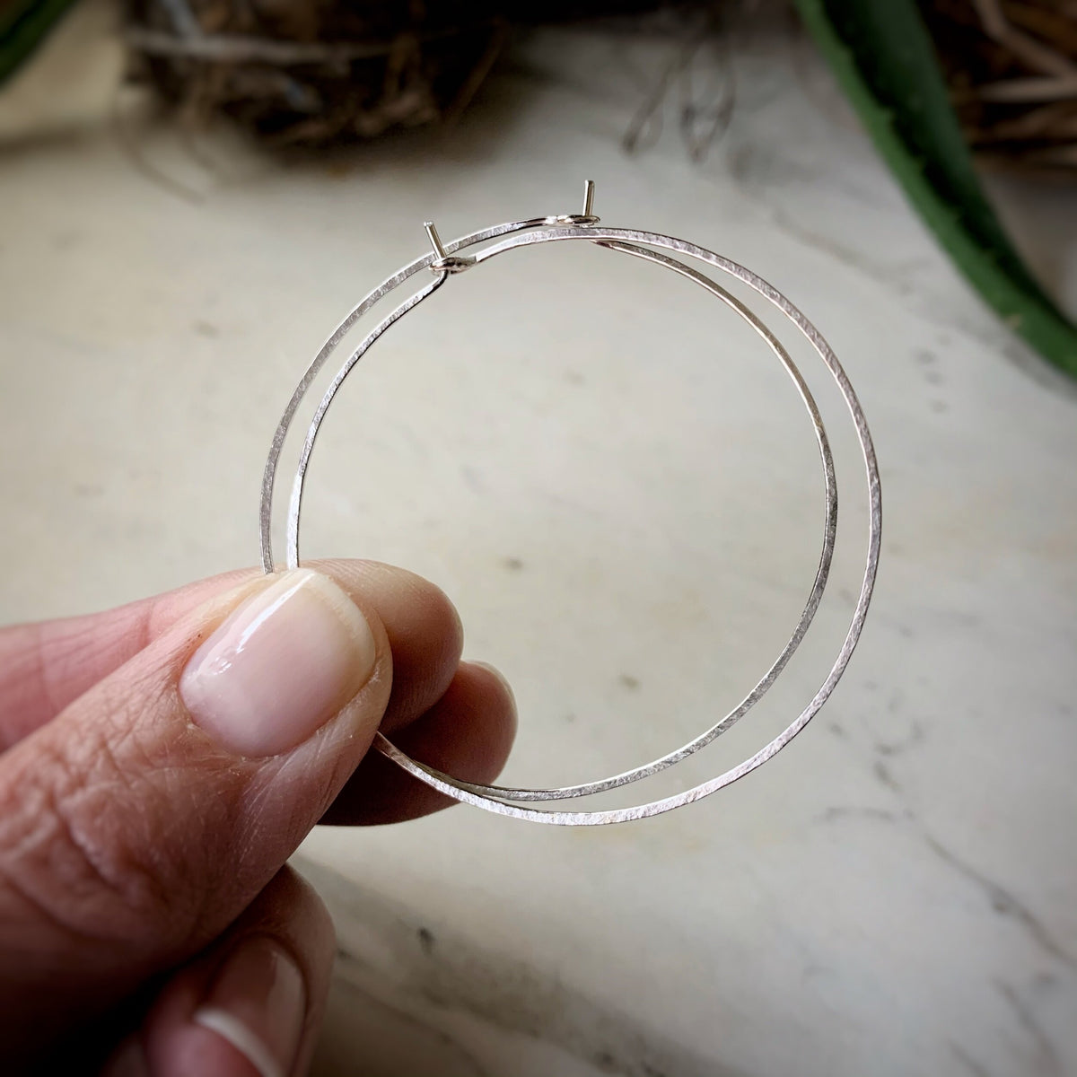 very large thin hammered sterling silver hoops. Shown being held in a hand for scale