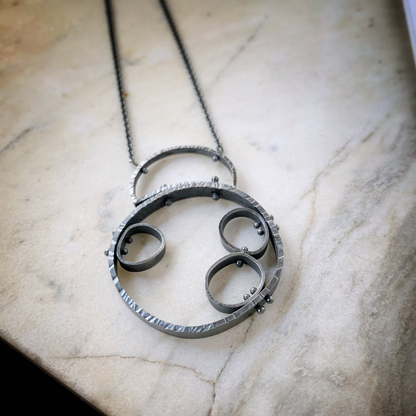 hammered organic circle with three more cells attached inside. Oxidized sterling silver modern