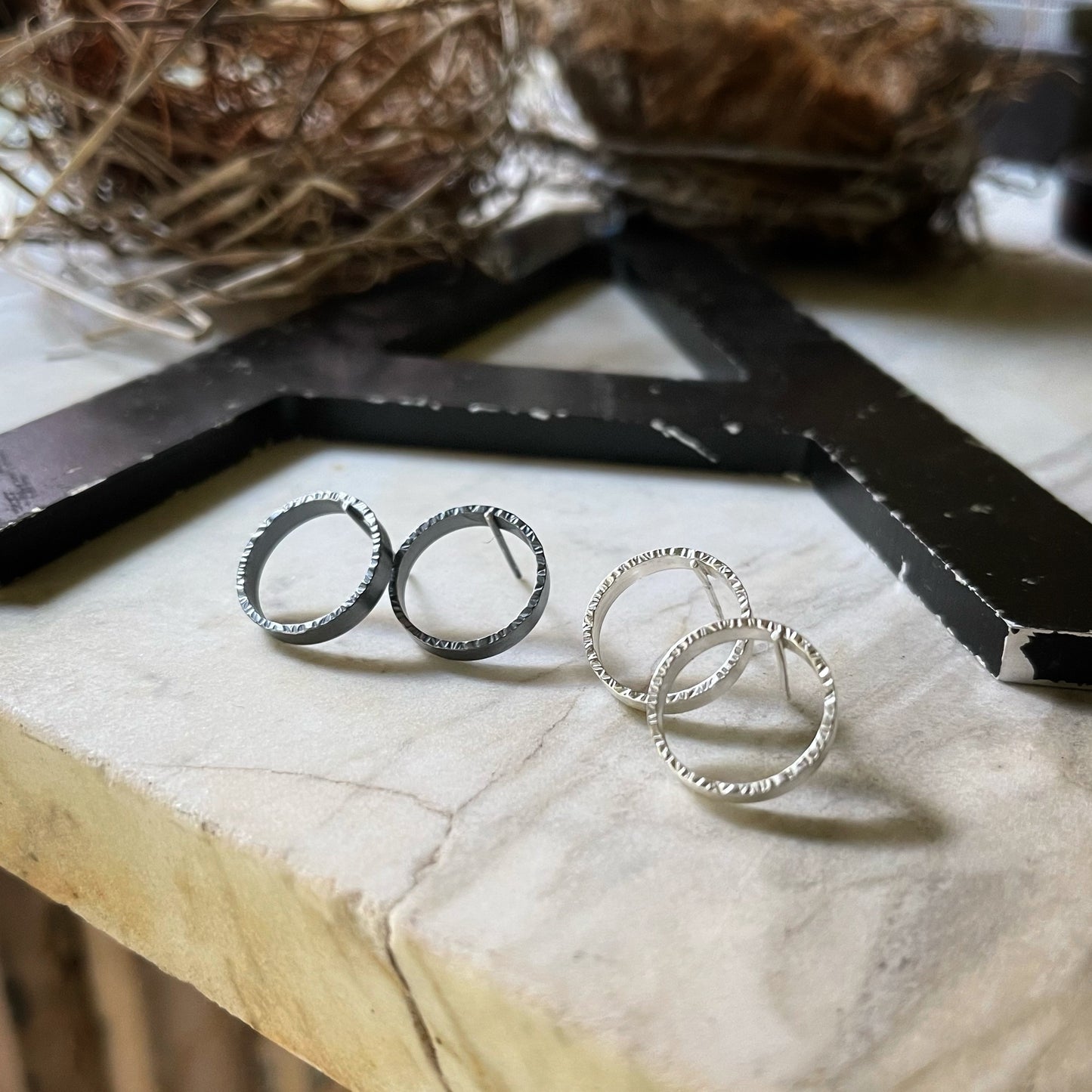 two pair of textured circle hoop earrings. one pair is bright silver and the other oxidized silver.