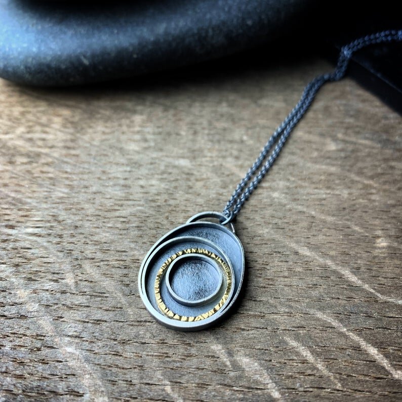 pendant with concentric circles, one in yellow gold, on a chain.