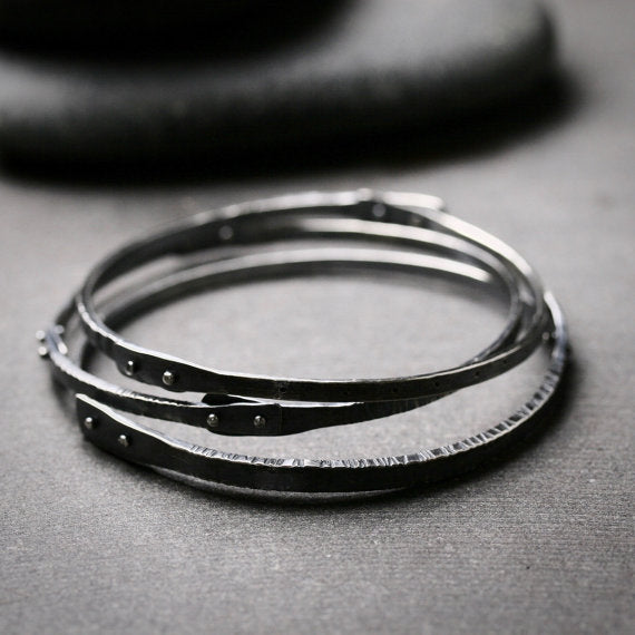 Detail of texture and rivets on oxidized silver bangle bracelets