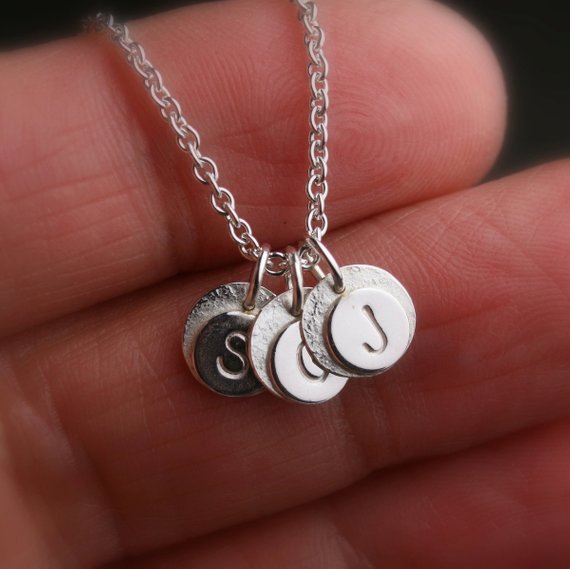 tiny hand stamped discs with initials and a hammer textured edge. Shown on a hand for scale
