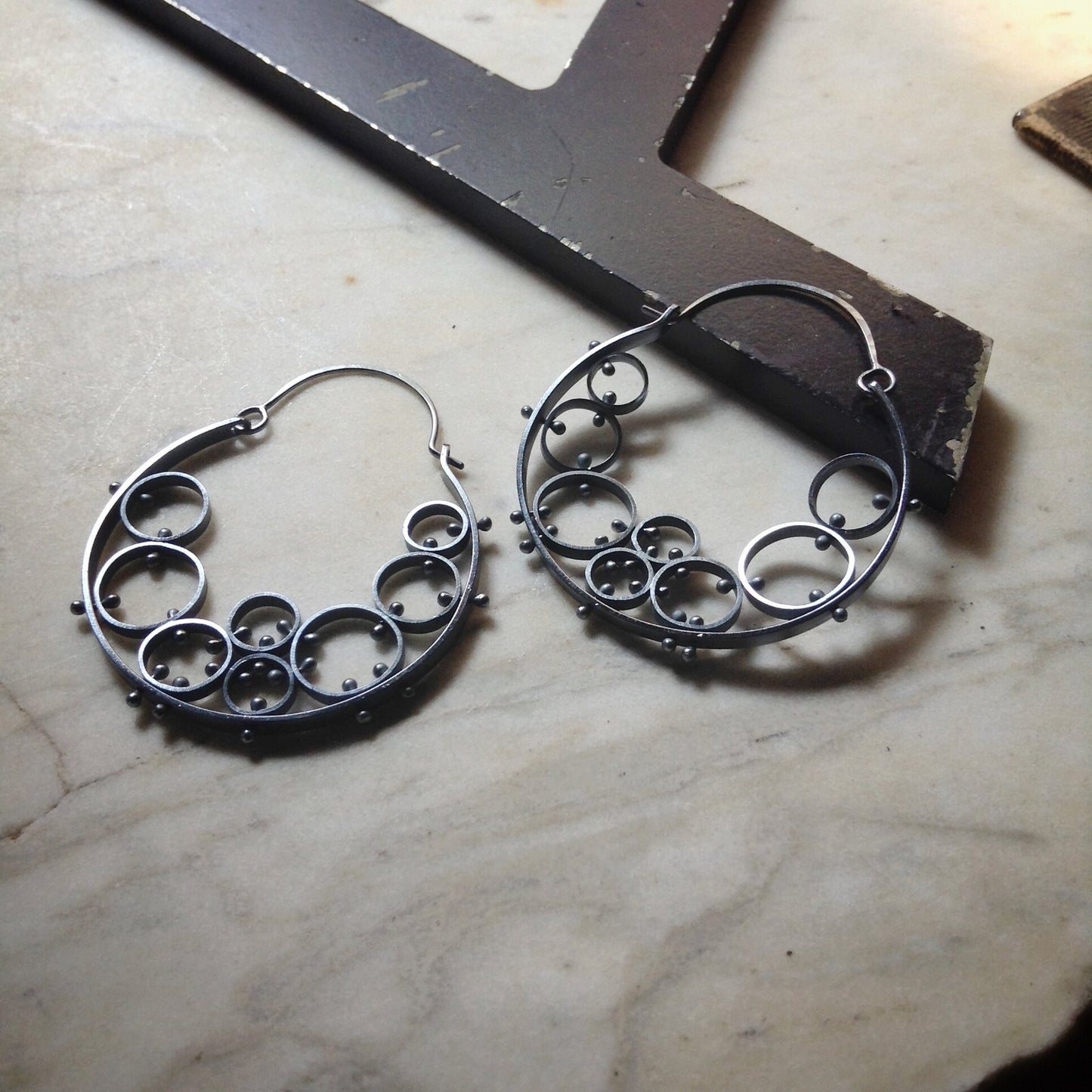 oxidized sterling silver hoop earrings. They are large and are made of many circles riveted together