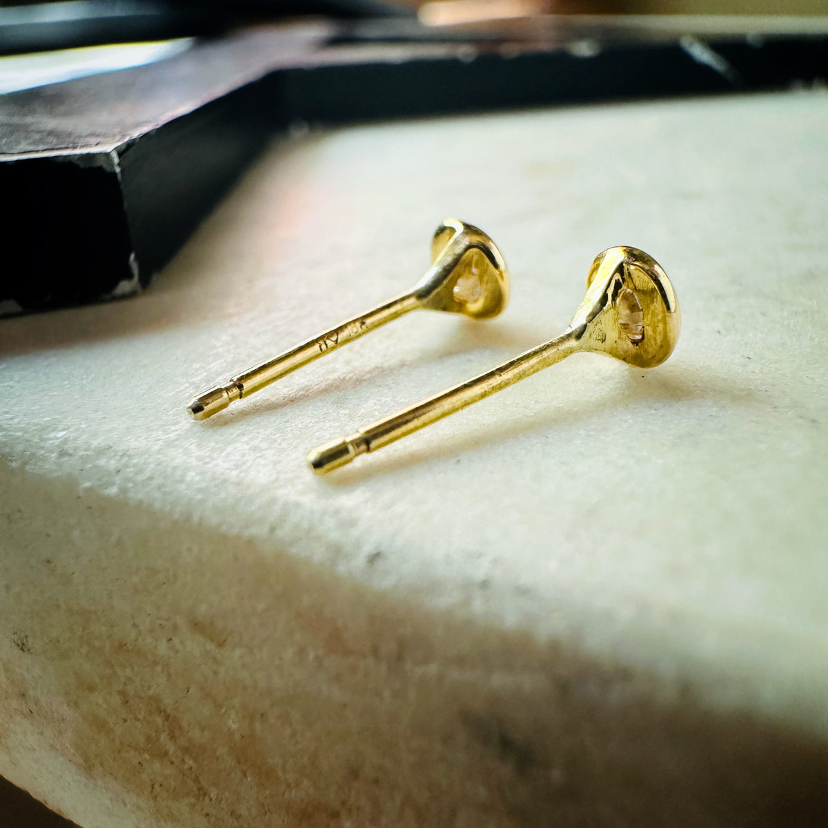 18k yellow gold 3mm Moissanite bezel set stud earrings on a marble background view from the back 
