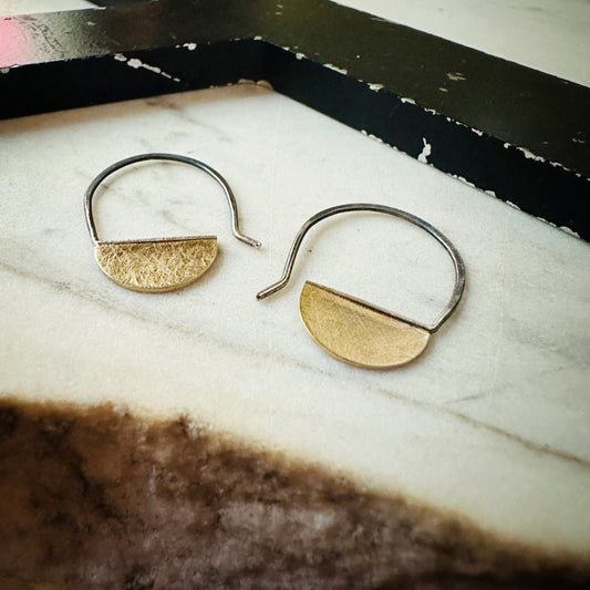 18k yellow gold half circle hoop earrings with oxidized ear wires on a marble surface