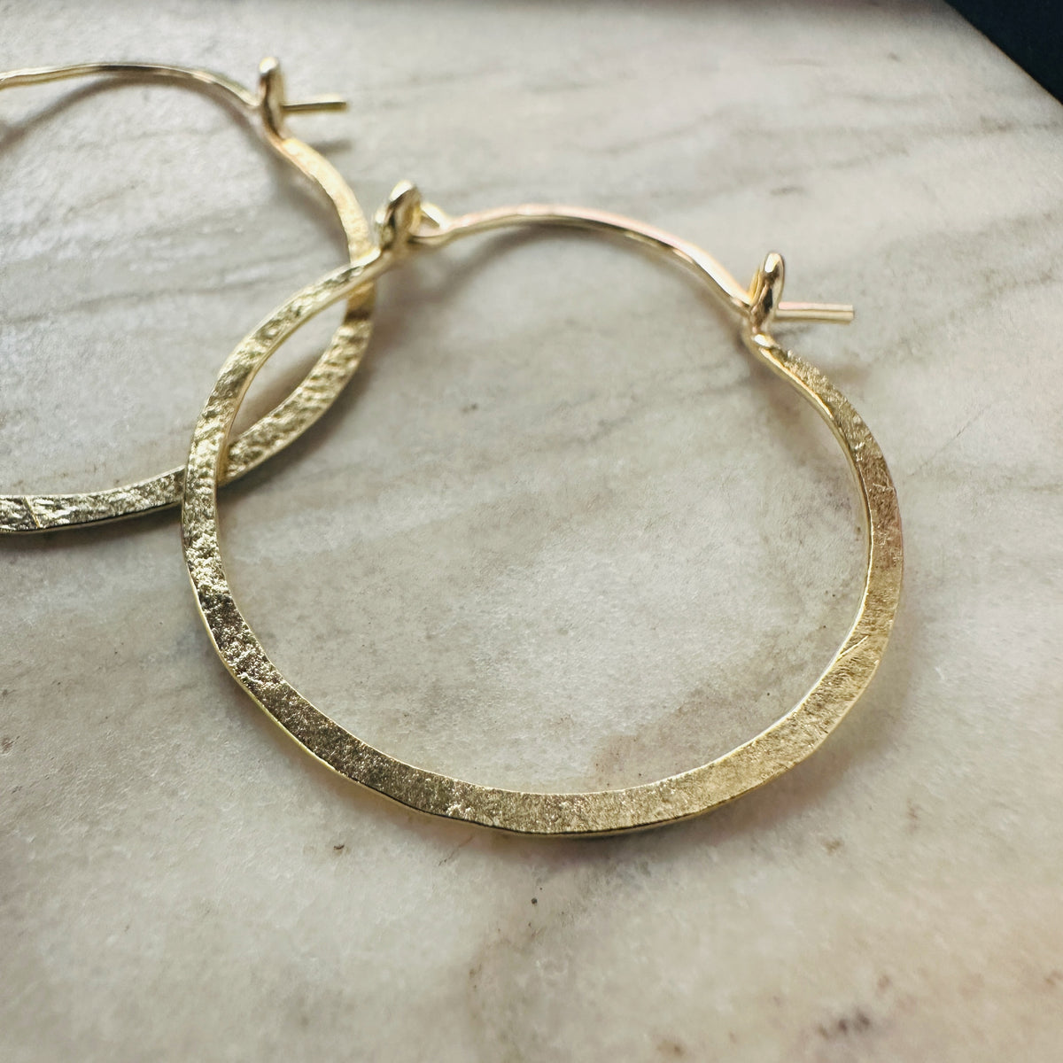 detal of 18k yellow gold hammered hoop earrings 