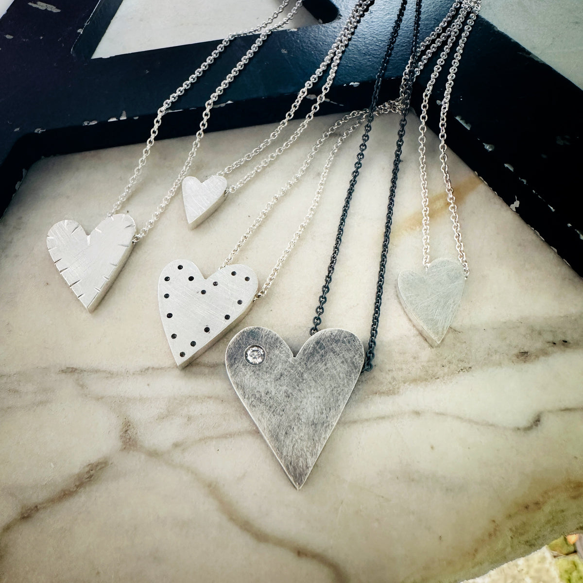 a collection of sterling silver heart pendants