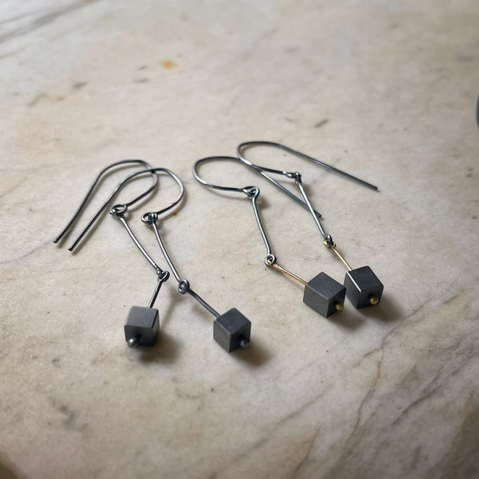 earrings in oxidized silver and gold wirh darkened silver cubes dangling at the end 