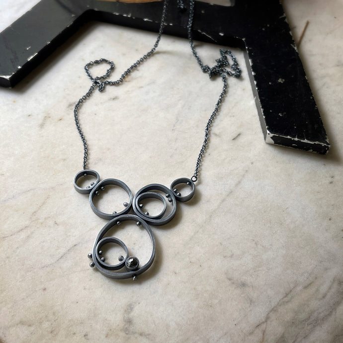 concentric circle and riveted pendant with bezel set hematite