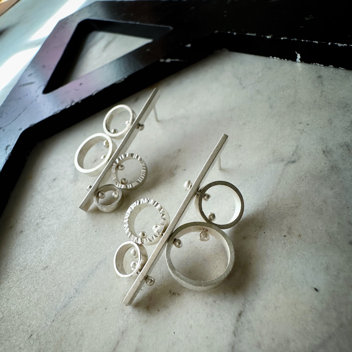 Sterling silver stud earrings with asymmetric cluster of circles and hammered texture detail, handmade by Ann HartleyStudio