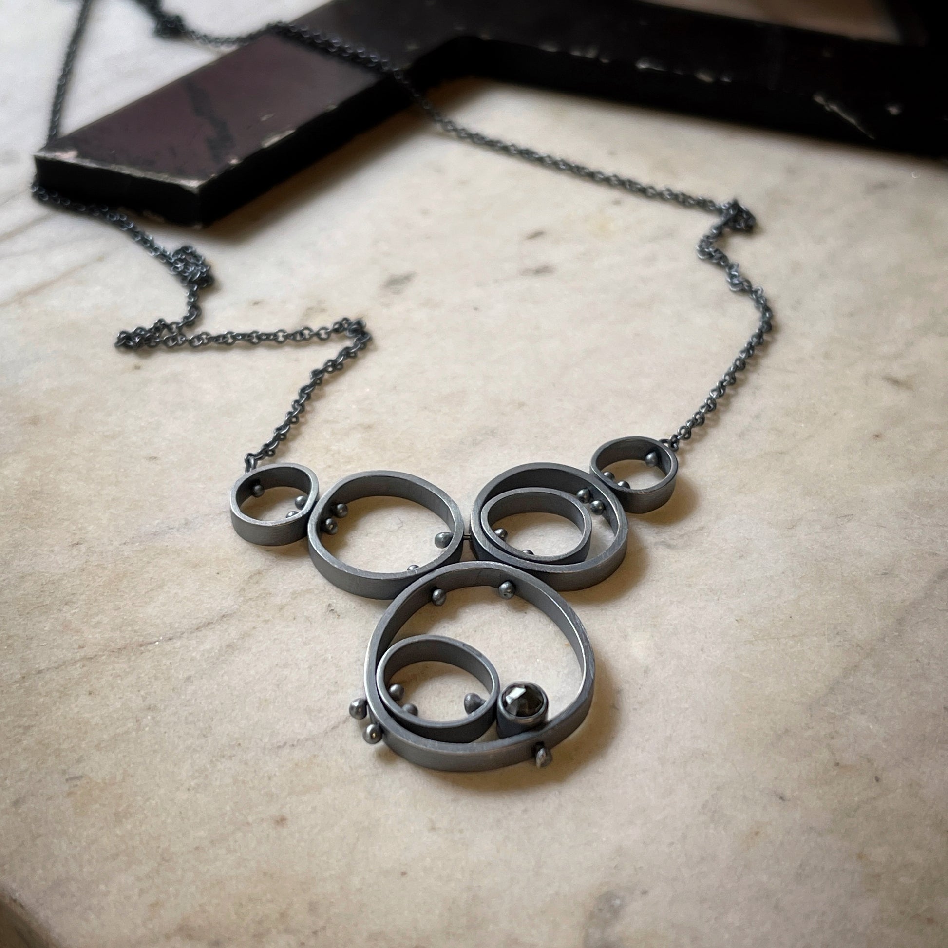 concentric circles held together with rivets and a bezel set hematite pendant