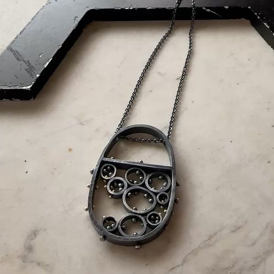 Oxidized sterling silver and gold pendant necklace with cellular circle design and gold rivet details, handmade by Ann Hartley Studio