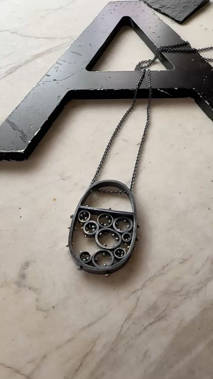 Oxidized sterling silver and gold pendant necklace with cellular circle design and gold rivet details, handmade by Ann Hartley Studio