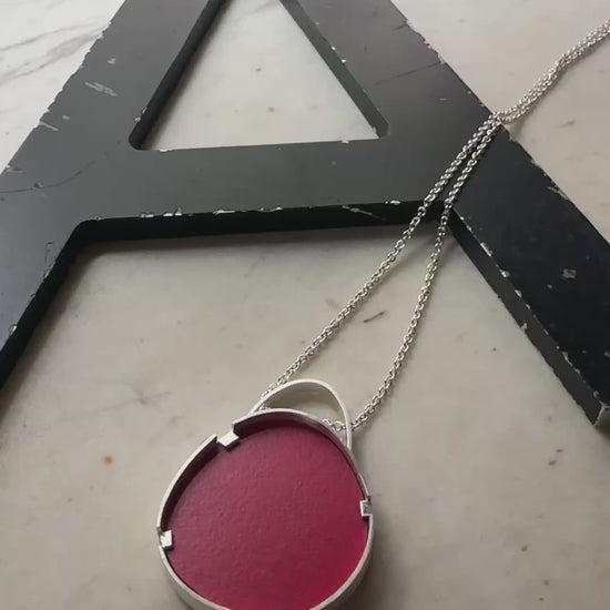 A sterling silver oval pendant with red formica center 