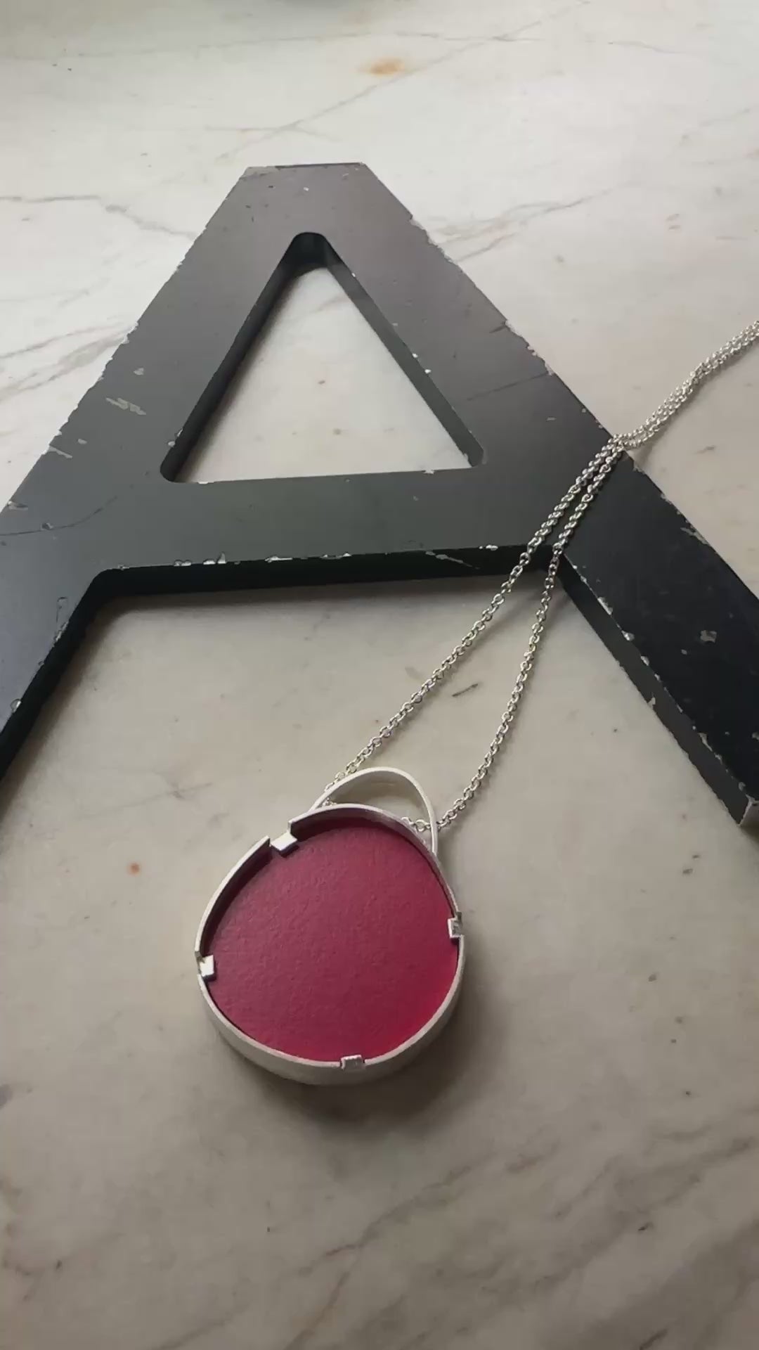 A sterling silver oval pendant with red formica center 