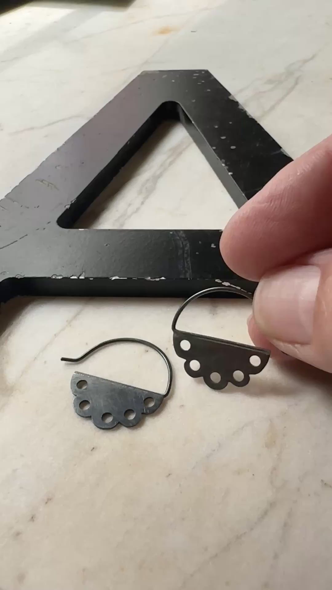 a video of a hand holding an oxidized silver pair of scalloped edge hoop earrings