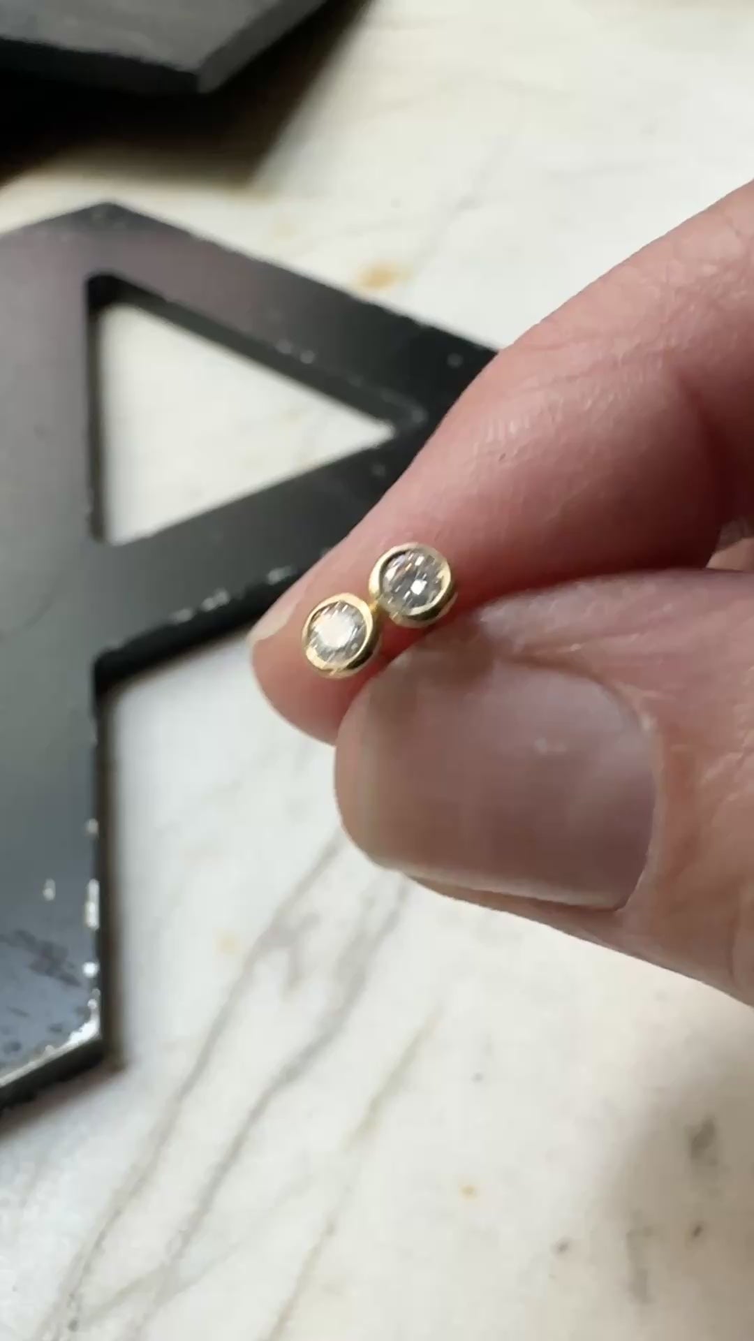 18k yellow gold 3mm Moissanite bezel set stud earrings on a marble background 