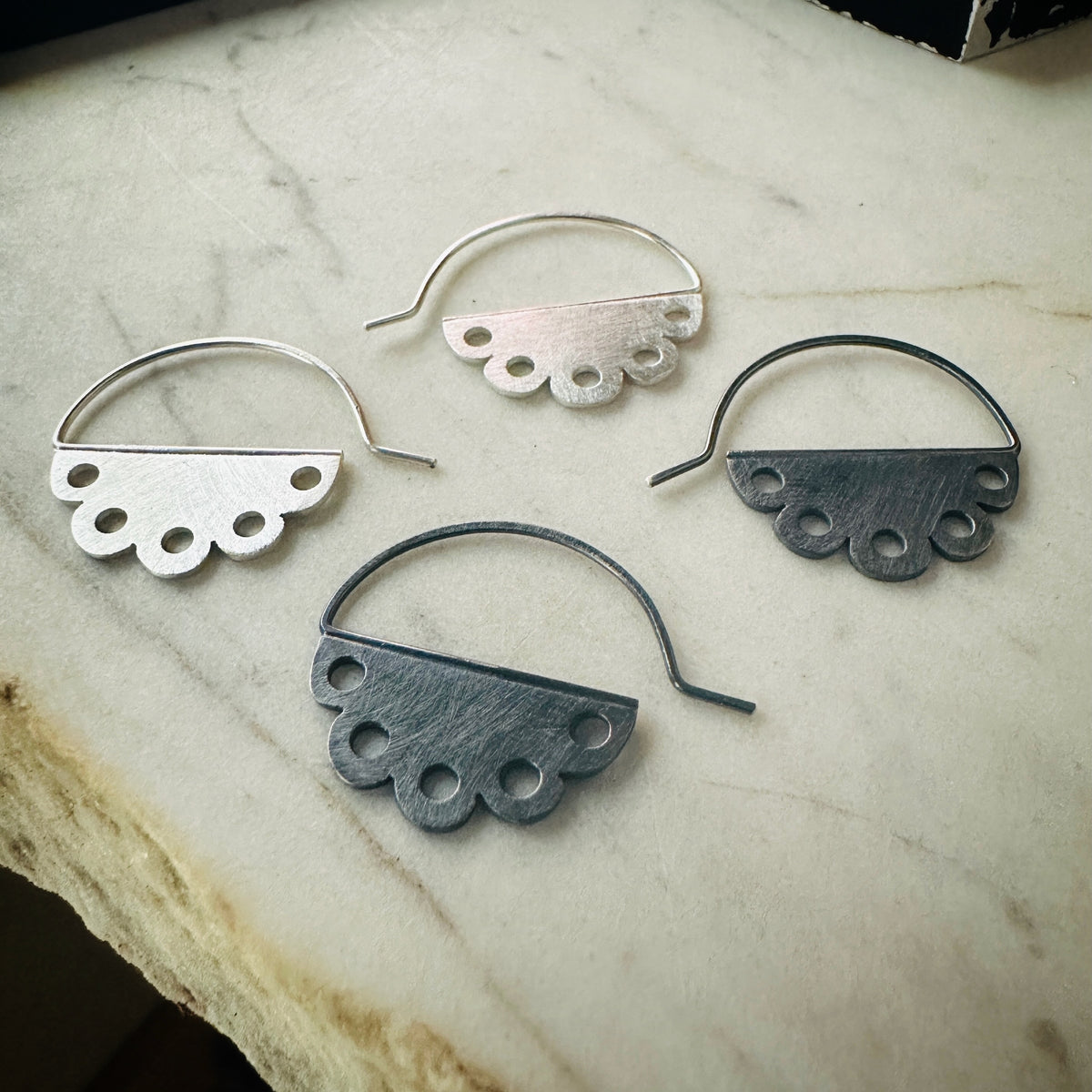two pair of scalloped earrings with pierced design. One pair bright silver and one pair oxidized silver 