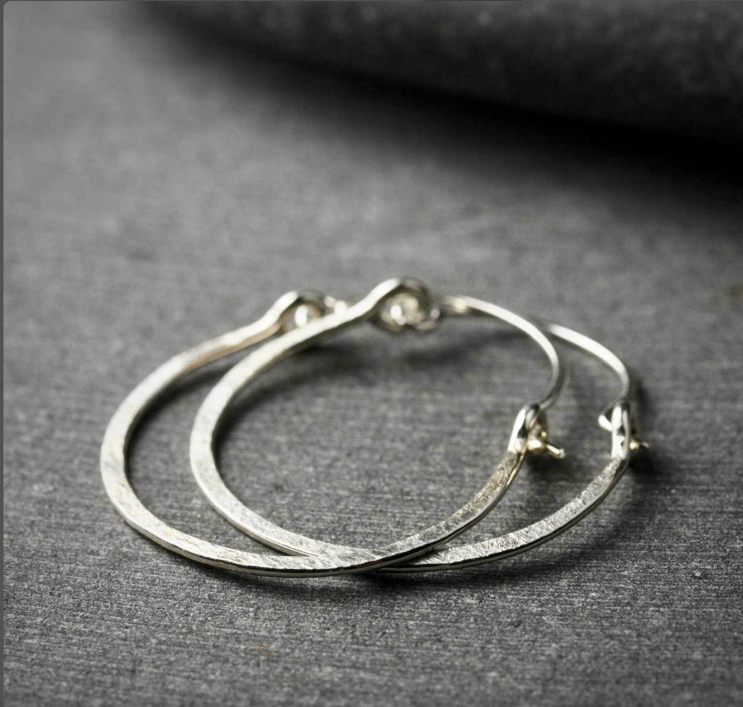 1 inch hammered hoop earrings lay on their side to show the hammered texture