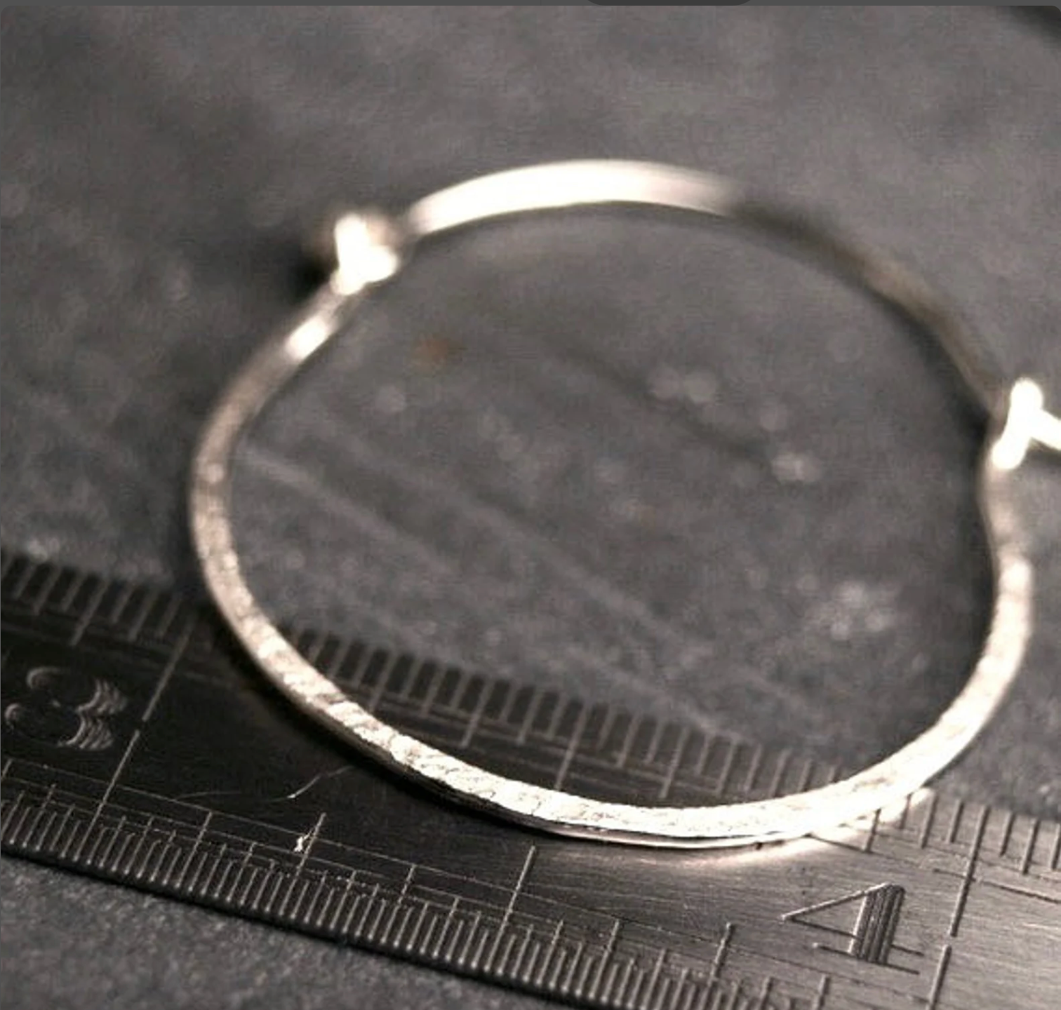 sterling silver hoop earring set on a ruler to show their 1" size