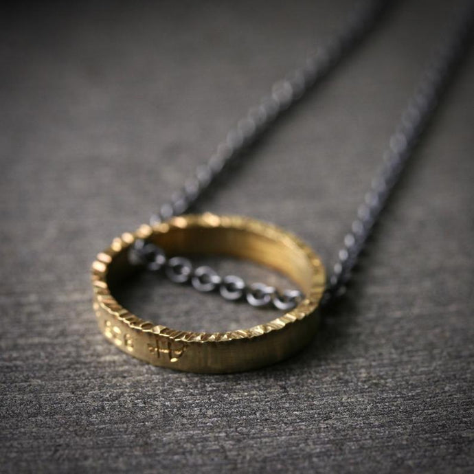 a one half inch circle pendant with a hammered texture on the front face. The chain is oxidized.