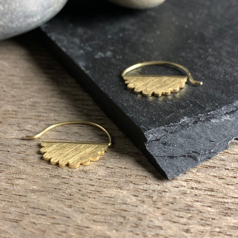 Showing the thickness of the 18k yellow gold scalloped edge cloud earrings.