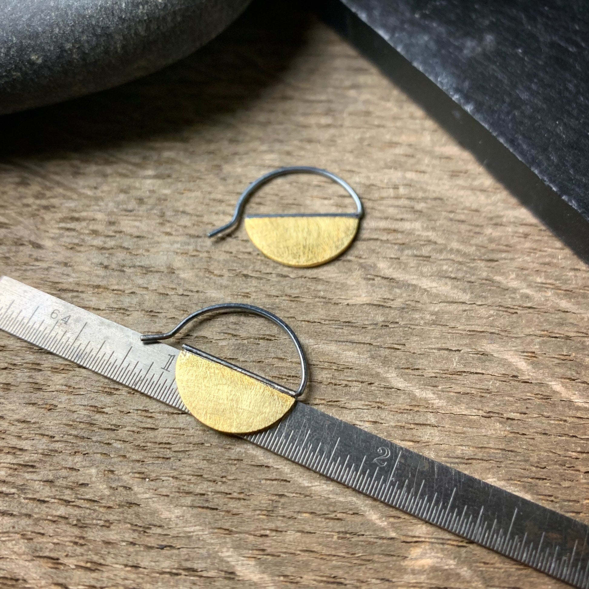 hoop earrings with half discs of 18k yellow gold with oxidized ear wires shown on a ruler for scale