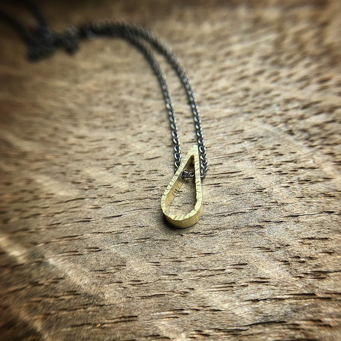 tiny 18k yellow gold teardrop shaped pendant with a hammered texture.  Sterling silver oxidized chain. 