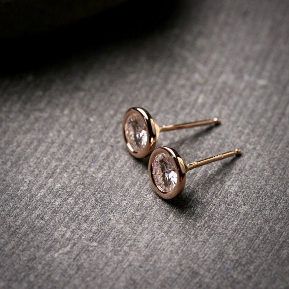 large 5mm Moissanite stud earrings in 14k rose gold bezels shown from the side to show posts