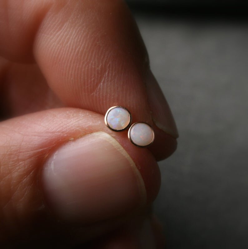 Australian opals bezel set in 14k rose gold shown being held in two fingers to show scale.