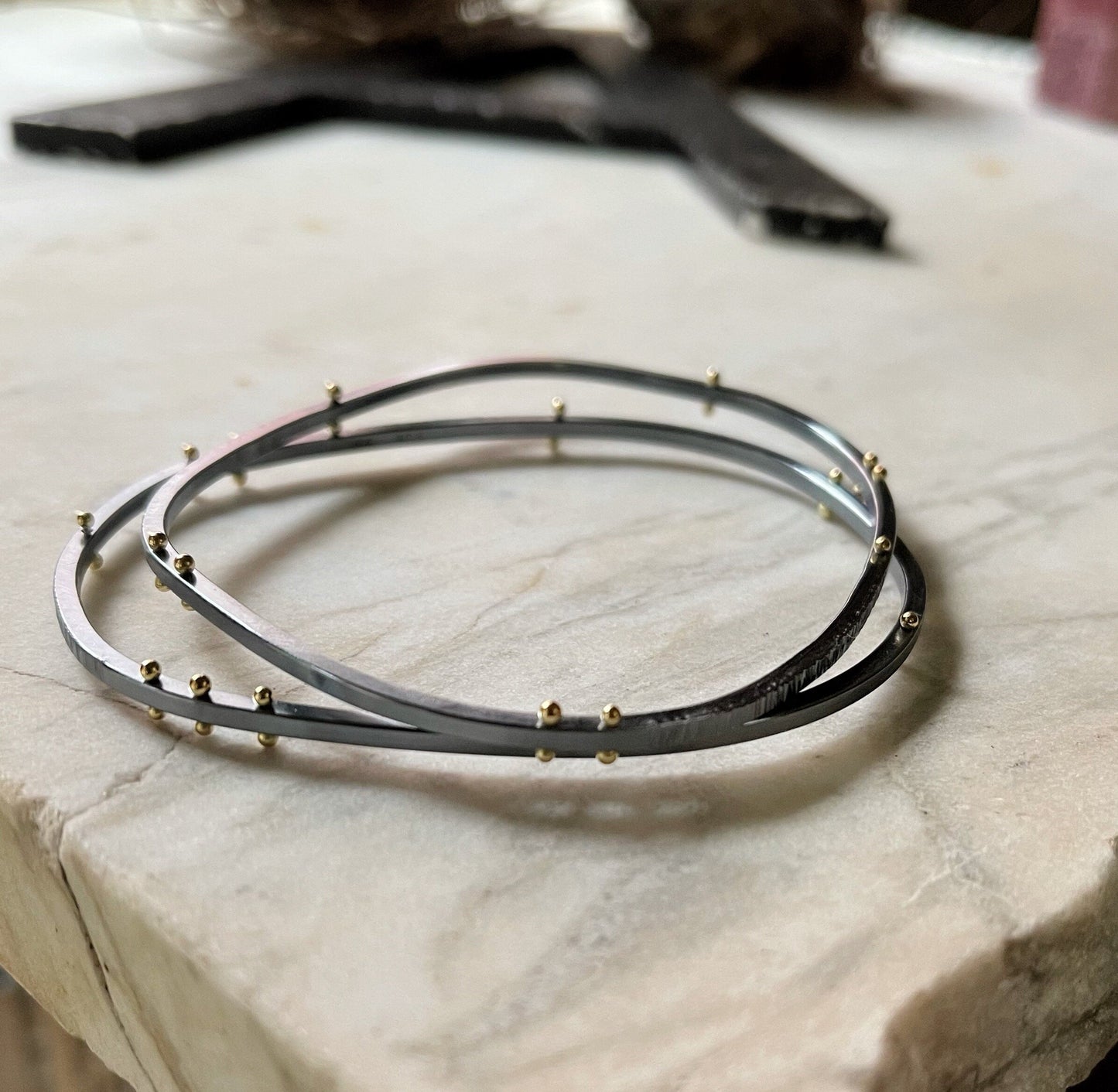 two asymmetrical bangle bracelets showing the option for gold rivets