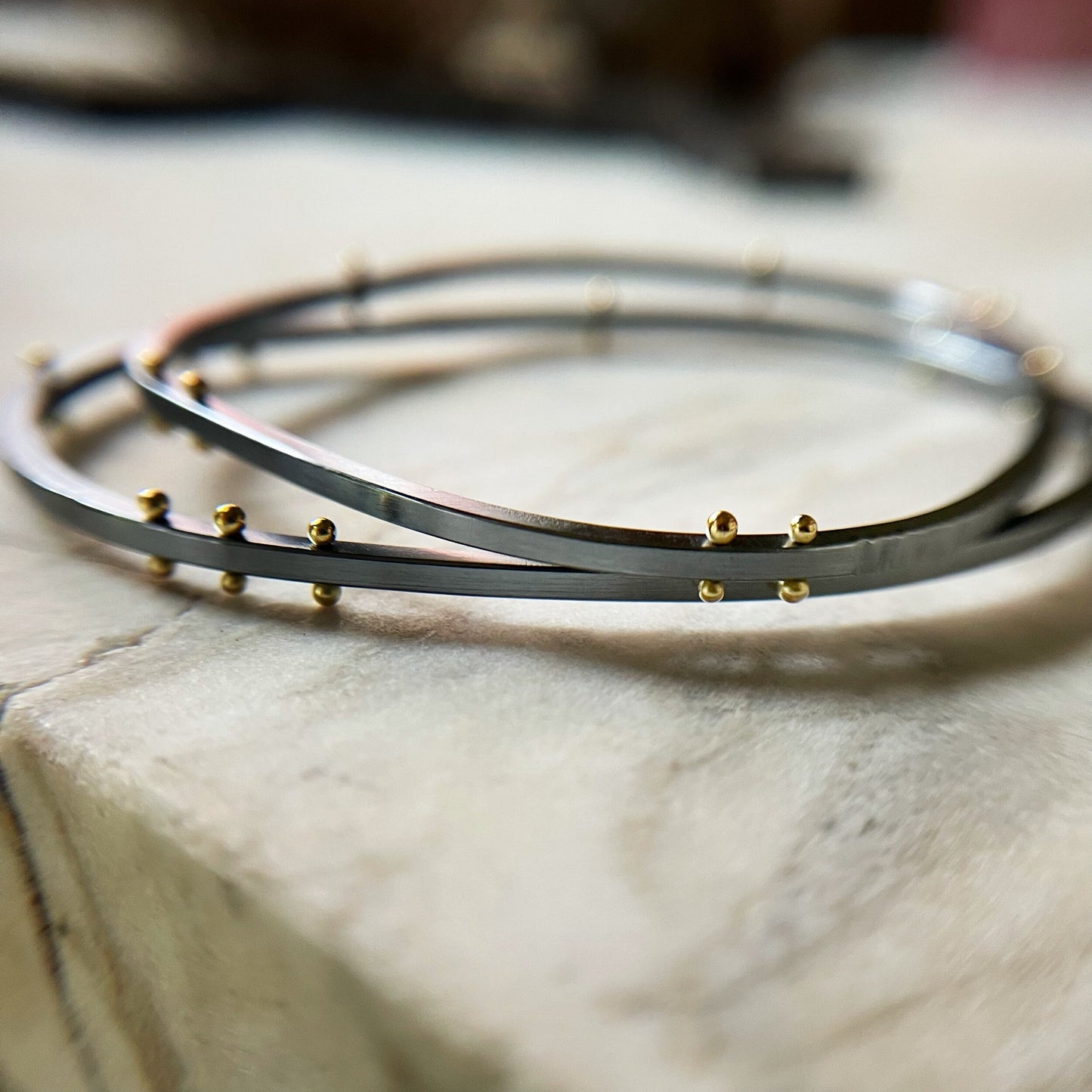 two bangle bracelets in oxidized sterling silver and gold rivets