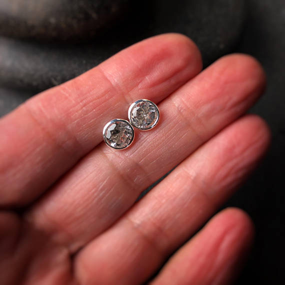 large white topaz sterling silver bezel set earrings shown on a hand to display scale