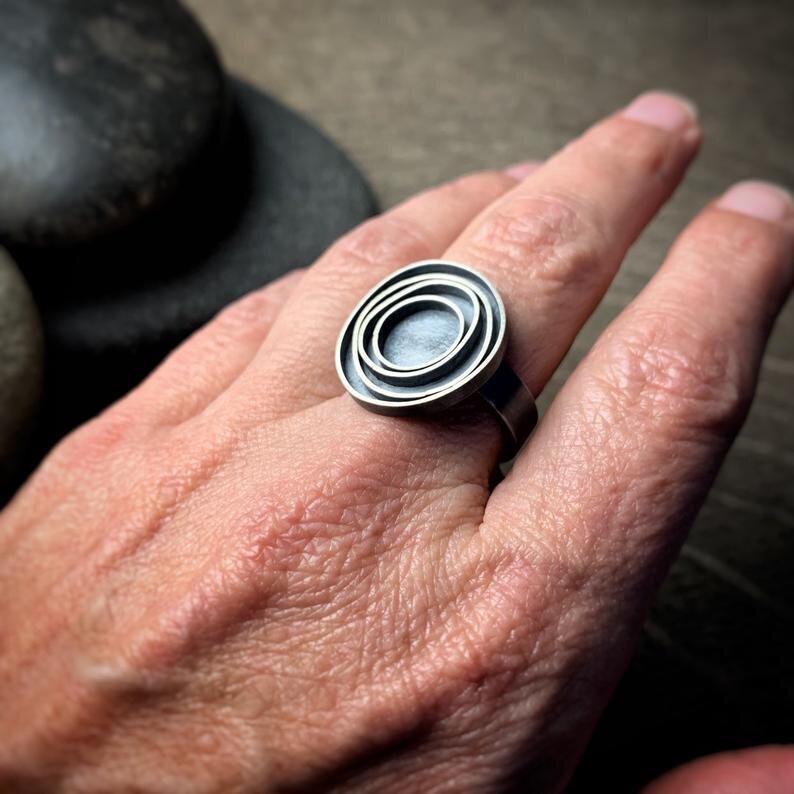 oxidized sterling silver ring with concentric circles shown on a hand for scale