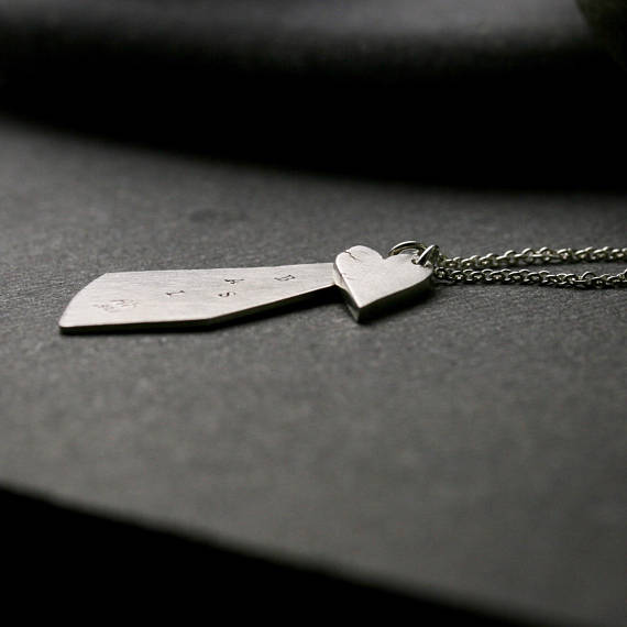 triangular shaped silver pendant with stamped initials and a chunky heart. shown from the side to show thickness