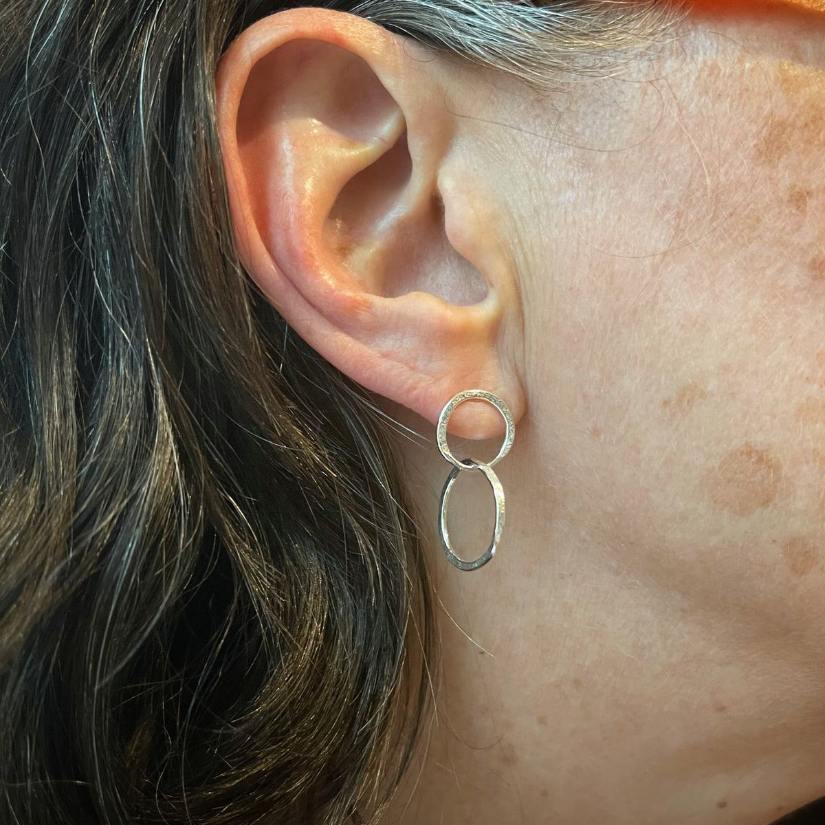 Sterling silver hammered hoop earrings worn on the ear