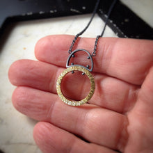 Load image into Gallery viewer, large textured gold circle with half circle sterling silver bail and silver chain pendant.  Shown in a hand for scale.
