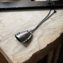Load image into Gallery viewer, a bell shaped pendant with a modern industrial look.  It&#39;s darkened silver with pin rivets and a chain
